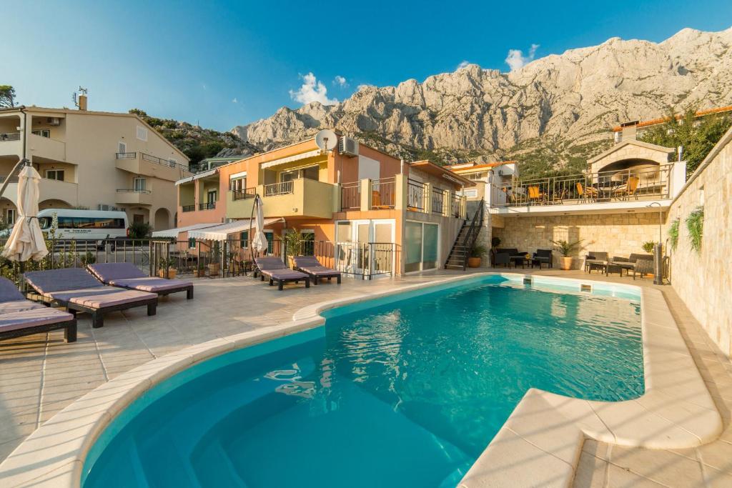 une piscine avec des montagnes en arrière-plan dans l'établissement Apartments Maša, à Makarska
