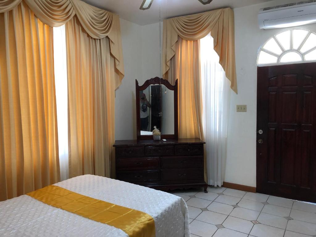 a bedroom with a bed and a dresser and a mirror at GoldenView Guesthouse Ocho Rios in Ocho Rios