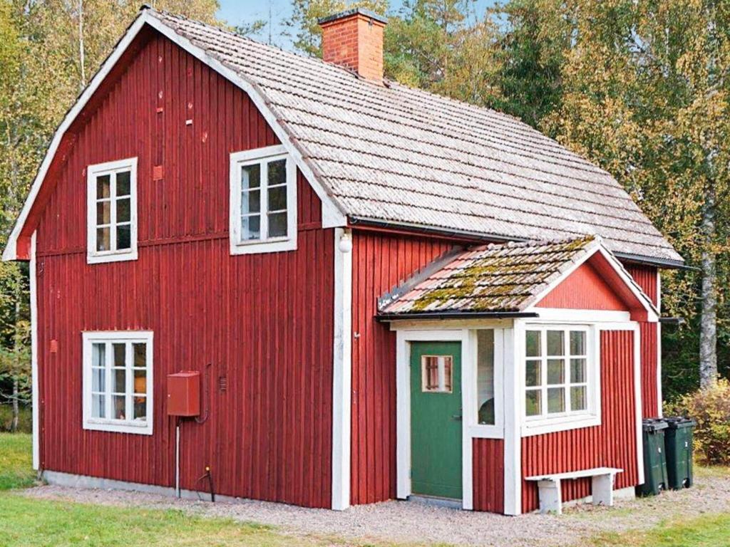 a red barn with white windows and a green door at 4 person holiday home in Sk rblacka in Skärblacka