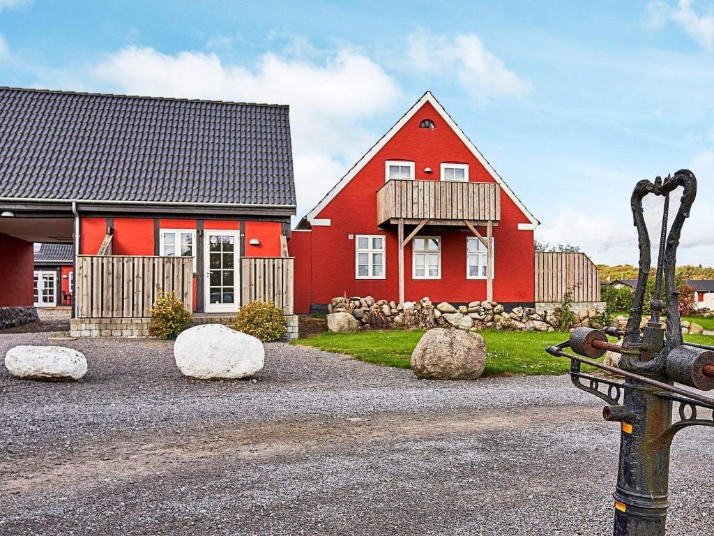 a red house with rocks in front of it at 5 person holiday home in Aakirkeby in Åkirkeby