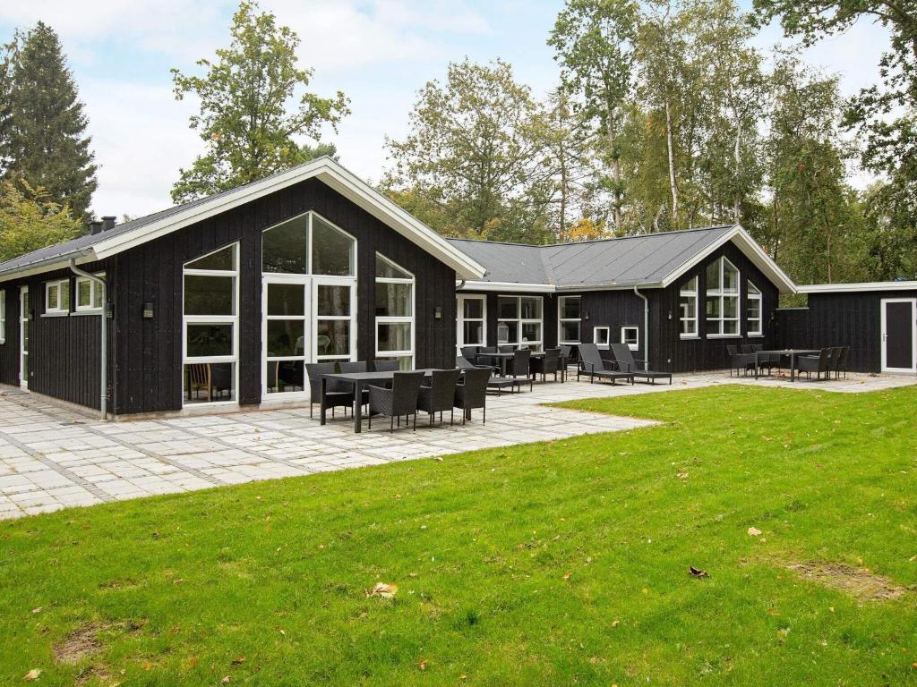 a black house with a patio and grass at 14 person holiday home in Str by in Strøby