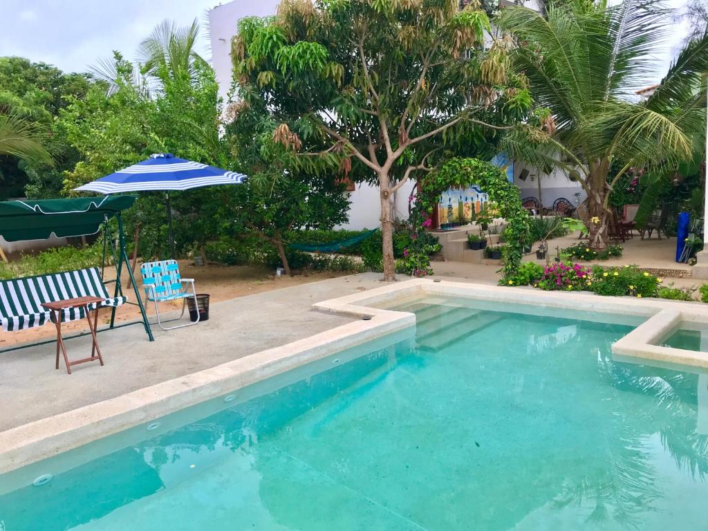 - une piscine avec un parasol, une table et des chaises dans l'établissement Keur Madior, à Ngaparou