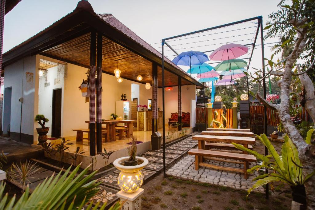 ein Haus mit einer Terrasse mit Tischen und Sonnenschirmen in der Unterkunft Double'D Hostel in Nusa Penida
