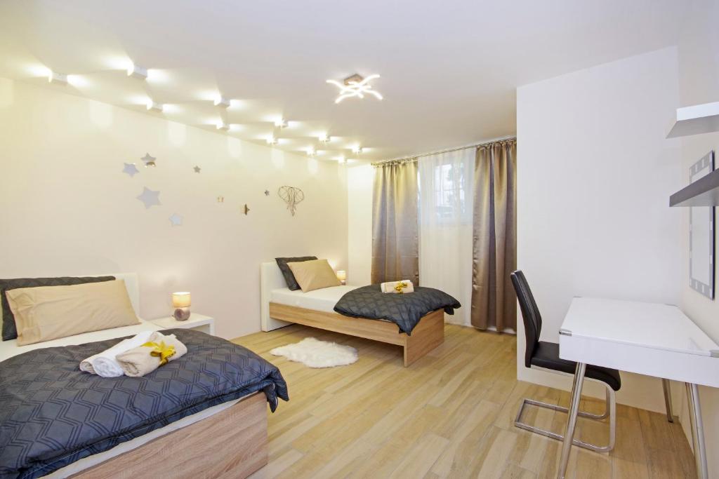 a bedroom with two beds and a desk at Split Symphony Garden: Modern, new Apartment (4+1), 5 min walk to ˝Firule˝ SAND BEACH, 12 min walk to CITY CENTER in Split