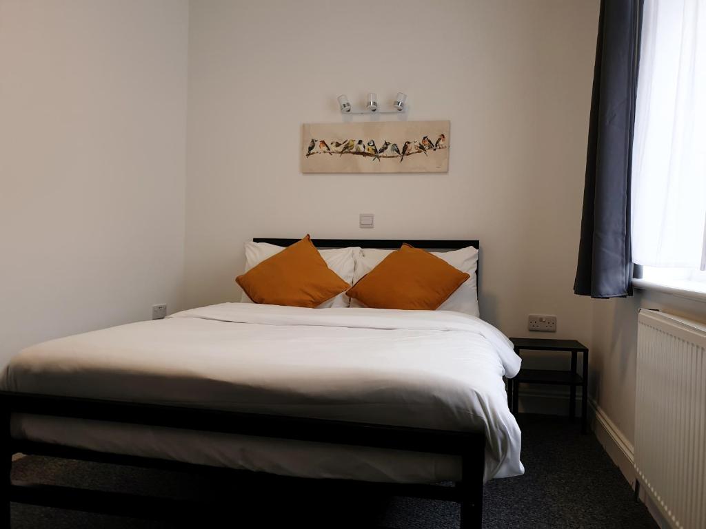 um quarto com uma cama com almofadas laranja em Wanstead Hotel em Londres