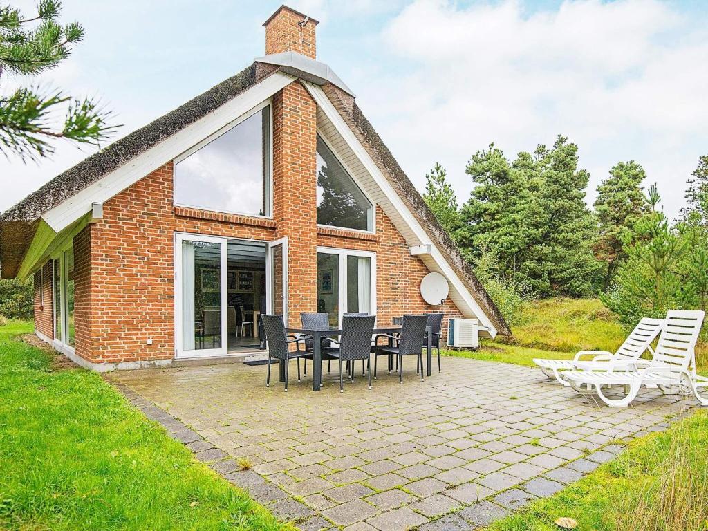 ein Haus mit einem Strohdach mit Stühlen und einer Terrasse in der Unterkunft 4 star holiday home in Rømø in Mølby