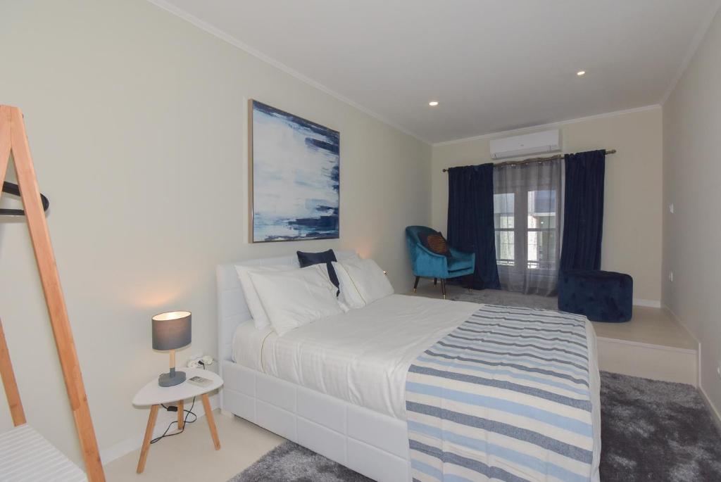 ein Schlafzimmer mit einem weißen Bett und einem blauen Stuhl in der Unterkunft Douro Prime Downtown in Vila Nova de Gaia