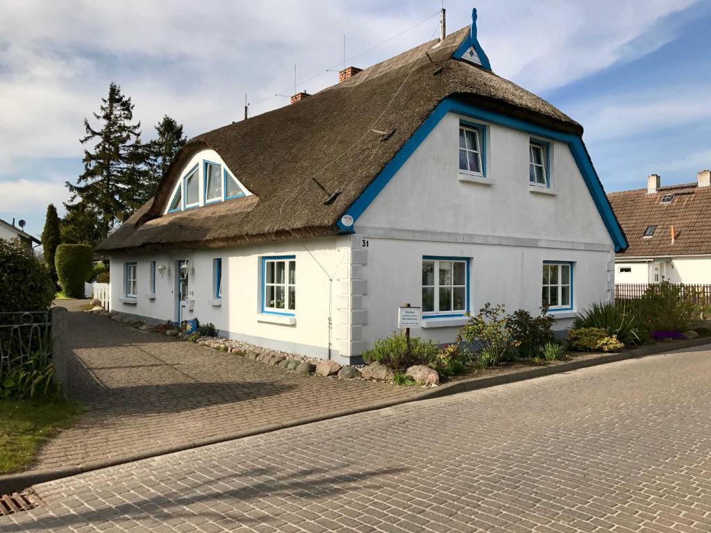 a white house with a thatched roof on a street at Historisches Kapitänshaus Breege in Breege
