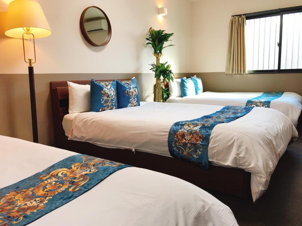 a hotel room with three beds and a mirror at Guest House One More Heart Kyoto Station South 3 in Kyoto