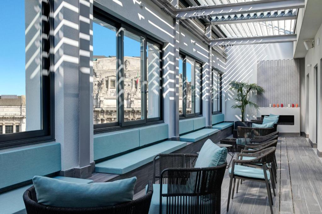iQ Hotel Milano في ميلانو: صف من الكراسي والطاولات في مبنى به نوافذ