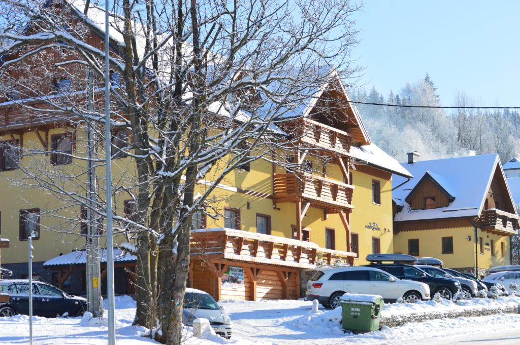 a large yellow building with cars parked in the snow at Chata Sudecka in Sienna