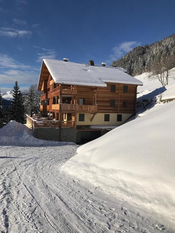 une cabane en rondins dans la neige avec une allée couverte de neige dans l'établissement L’énergie Tranquillisante, au Grand-Bornand