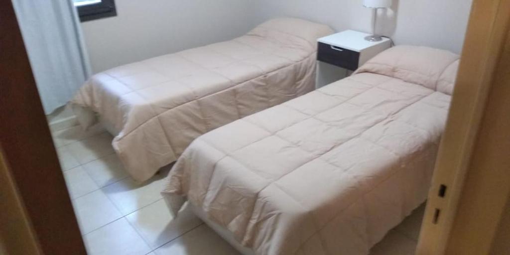 two beds with white sheets in a room at Calidez in Villa Carlos Paz