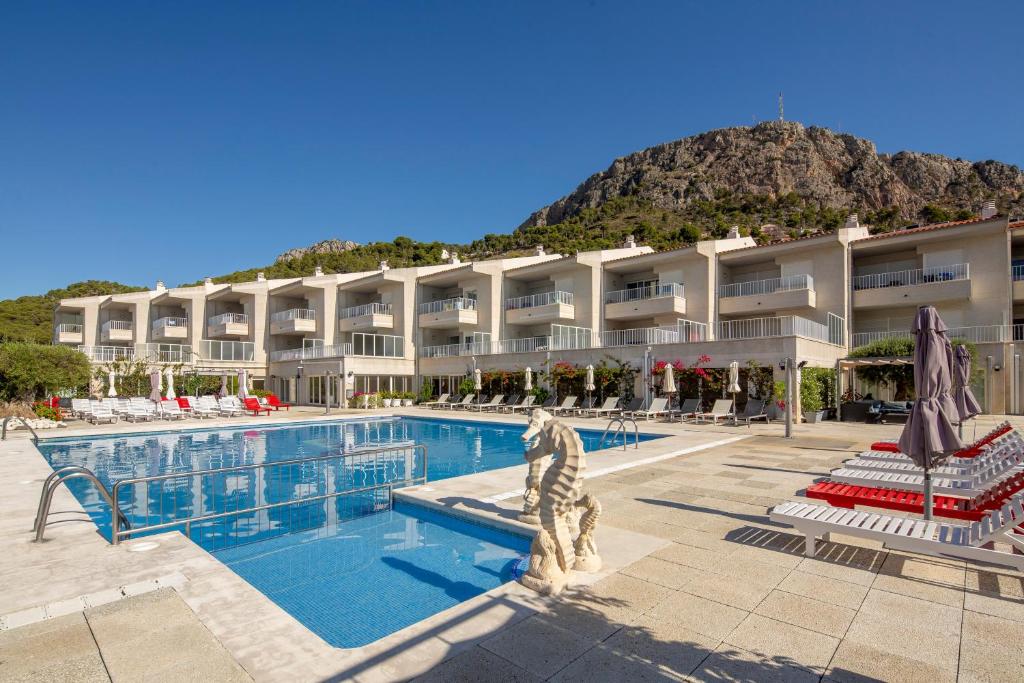 a hotel with a swimming pool with a mountain in the background at Apartamentos Centremar in L'Estartit