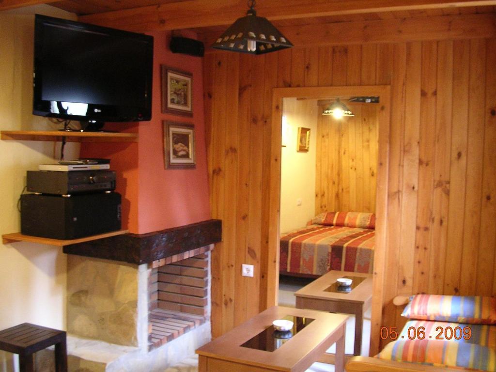 a living room with a fireplace and a bedroom at Casas El Suspiro in Zahora