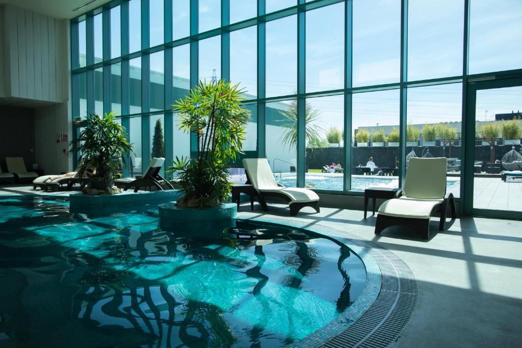 a large swimming pool in a lobby with chairs and windows at The Malvern in Great Malvern