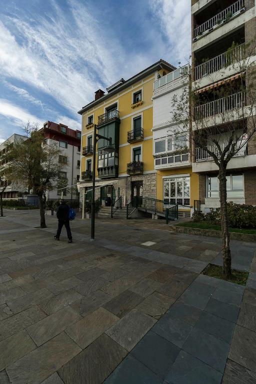 a man walking in front of a yellow building at Paseo Butrón by Basquelidays in Hondarribia