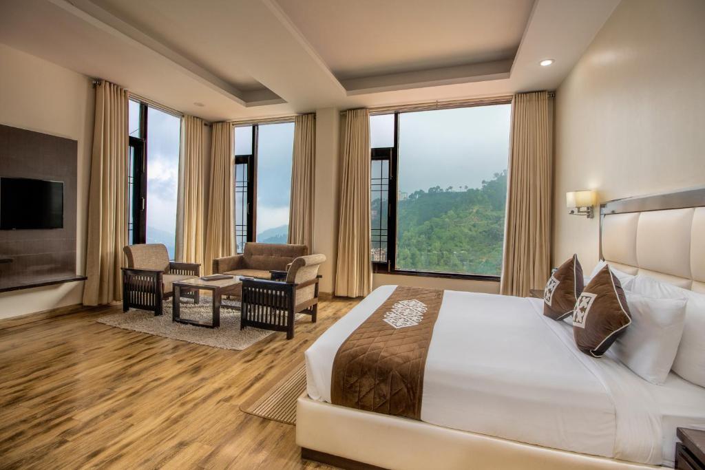 Cette chambre comprend un lit et une grande fenêtre. dans l'établissement Snow Valley Resorts Shimla, à Shimla