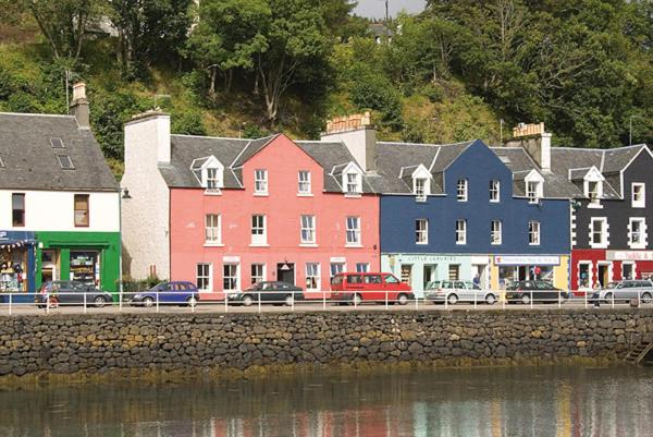 een rij kleurrijke huizen naast een waterlichaam bij Tobermory Youth Hostel in Tobermory