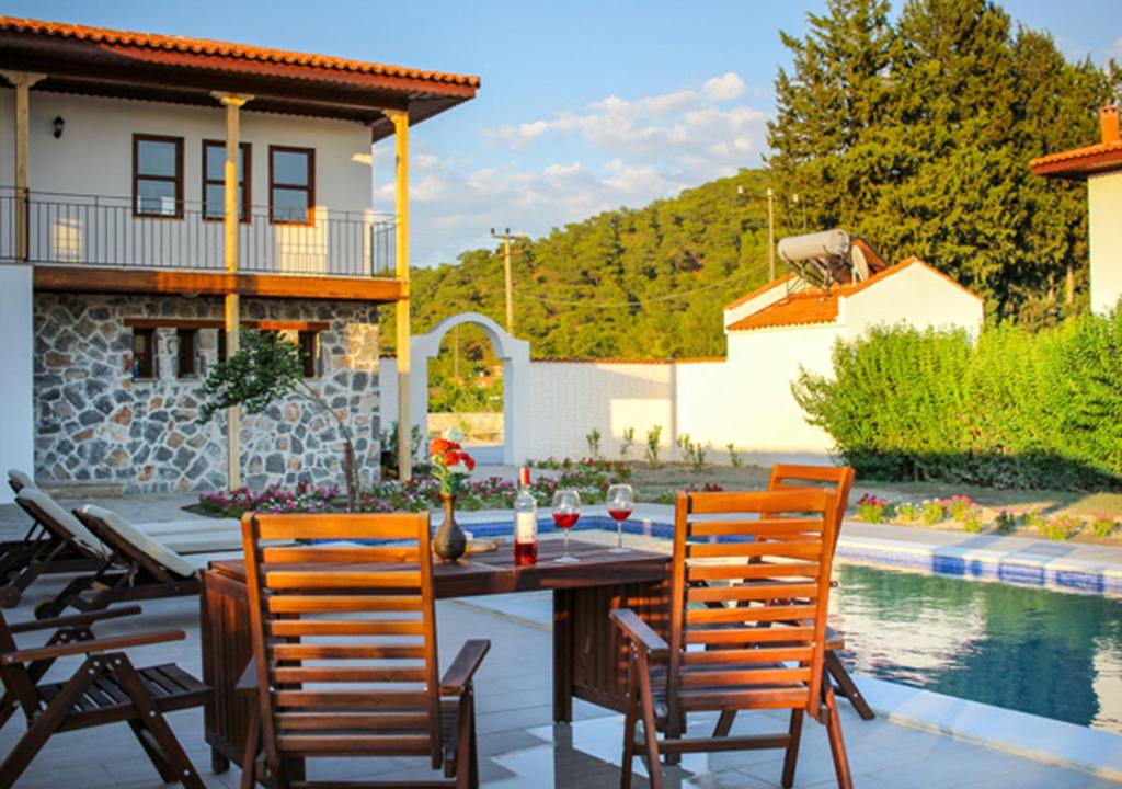 um pátio com uma mesa e cadeiras ao lado de uma piscina em Aydos Konakları em Muğla