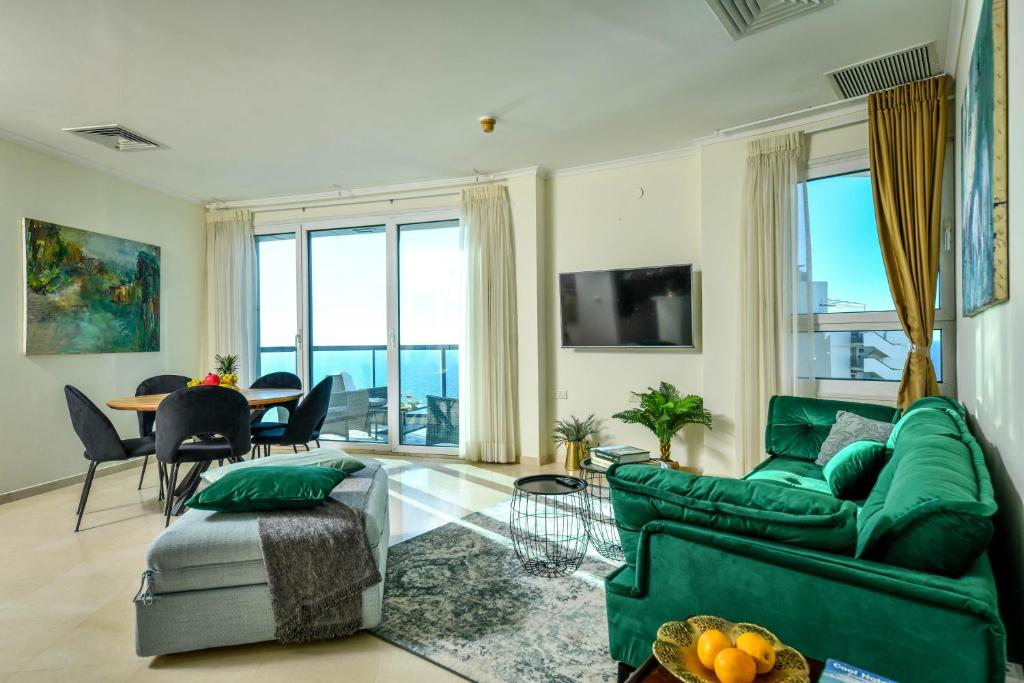a living room with a green couch and a table at Picturesque 3BR Apt w Balcony & Parking Near Beach by Sea N' Rent in Tel Aviv