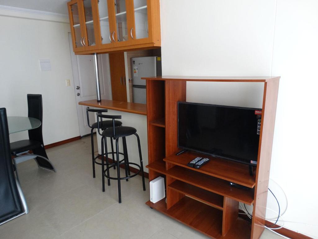 ein Wohnzimmer mit einem TV, einem Tisch und Stühlen in der Unterkunft D12-7 Depto diario a pasos de la playa Arica in Arica