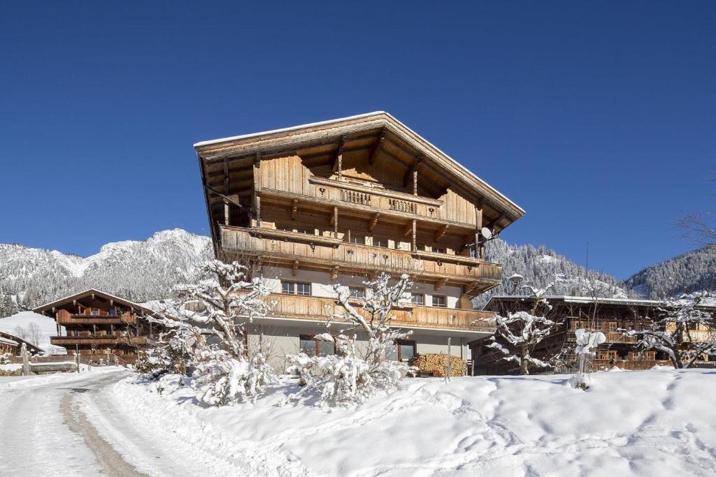 ein großes Holzgebäude im Schnee mit einer Straße in der Unterkunft Lederer Zuhaus in Alpbach