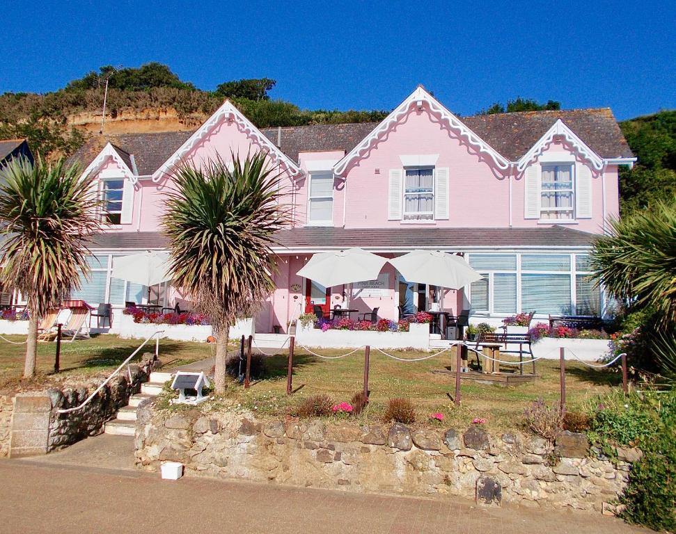 een roze huis met palmbomen ervoor bij Pink Beach Guest House in Shanklin