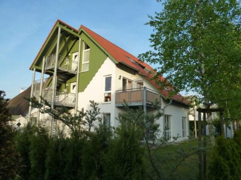 a large white house with a red roof at Ferienwohnung Heiden _ 100m bis zu in Ostseebad Karlshagen