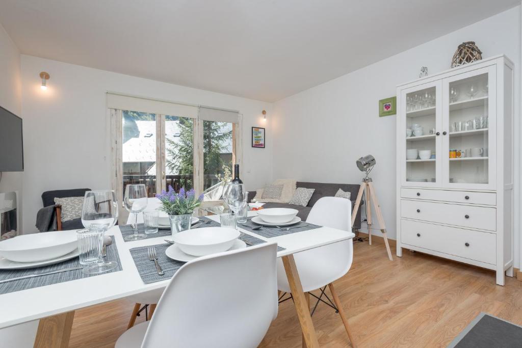 a dining room with a white table and white chairs at Apartamento Avet in El Tarter