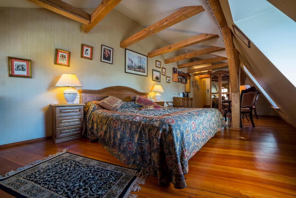 Shakespeare Boutique Hotel — Attic bedroom with exposed wooden beams, sloped ceiling, patterned bedspread, bedside lamps, hardwood floors and built-in shelving