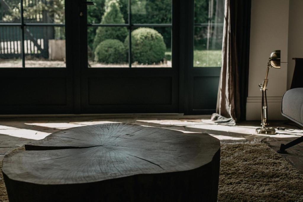Cette chambre dispose d'une table basse entourée d'arbres devant une porte. dans l'établissement La Dime de Giverny - Cottages, à Giverny