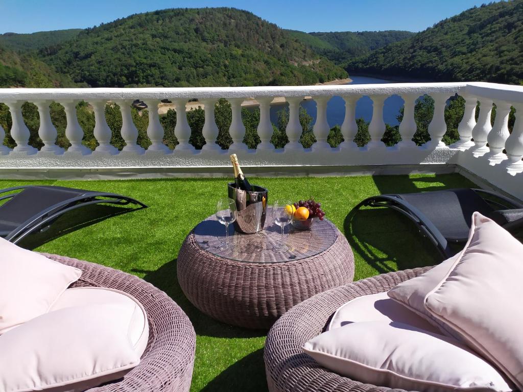 Miremont的住宿－Ma villa au bord de l'eau，阳台配有藤椅和1张带1瓶葡萄酒的桌子。