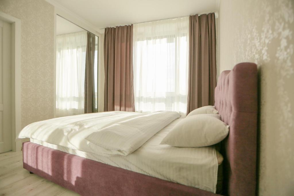 a bed in a bedroom with a large window at ЖК Славутич апарти in Kyiv