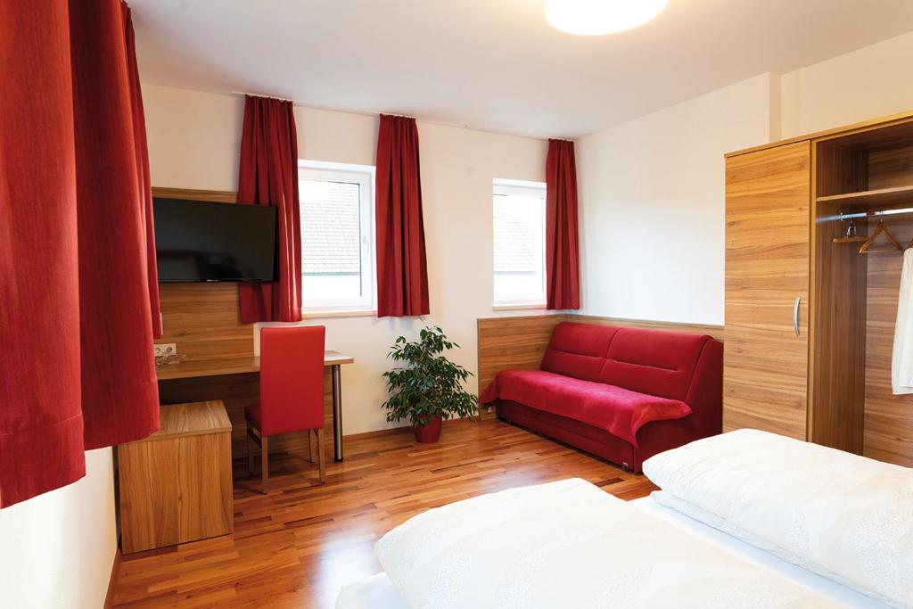 a bedroom with a bed and a red couch and a desk at Hotel Mauernböck in Rottenbach