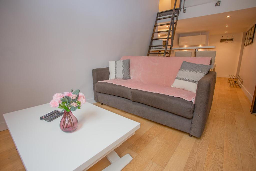 a living room with a couch and a table with a vase of flowers at Le Duplex in Versailles