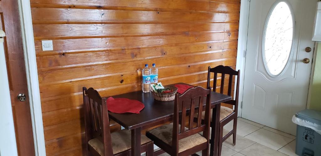 une salle à manger avec un mur en bois et une table avec des chaises dans l'établissement Unit 5/6 Private Apartment - Roseau, à Roseau