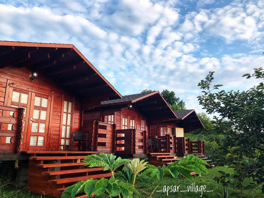 a wooden house with a bunch of chairs in front at Guest House Apsar Village in Novy Afon