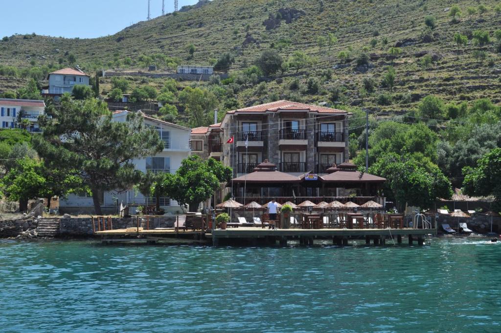 un hotel en un muelle en el agua junto a una montaña en Veranda Hotel, en Bozburun