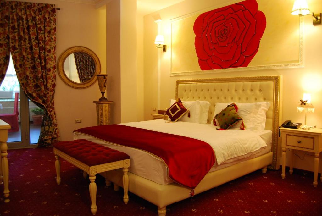 a bedroom with a large bed with a red rose painting on the wall at 2 KITARRAT Boutique Hotel & SPA in Durrës