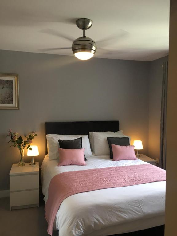 a bedroom with a large bed with pink and white pillows at La Belle Three bedrooms Basildon in Basildon