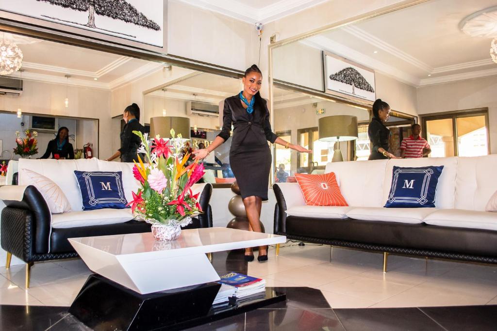 Eine Frau steht in einem Wohnzimmer mit einer Blumenvase in der Unterkunft Hotel M'Rode in Lomé