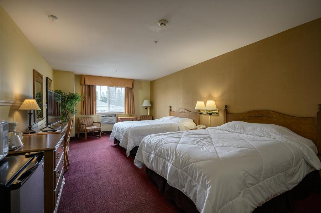 Cette chambre comprend deux lits et une télévision. dans l'établissement Three Rivers Inn Sedro Woolley, à Sedro-Woolley