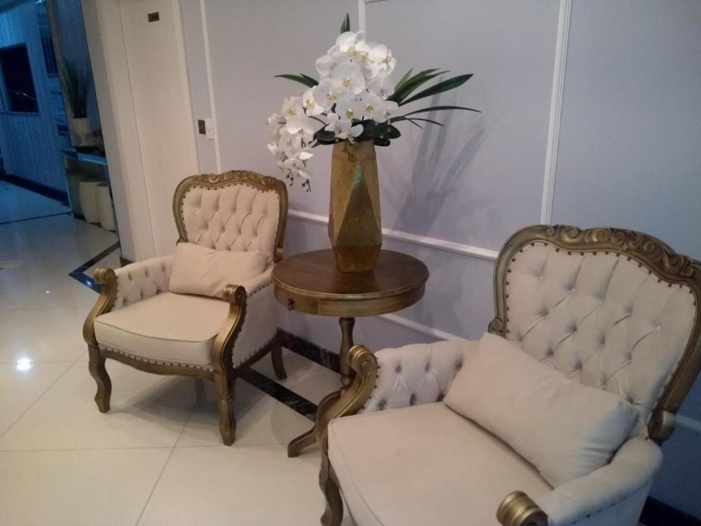 dos sillas y una mesa con un jarrón de flores en Residencial Maristela, en Bombinhas