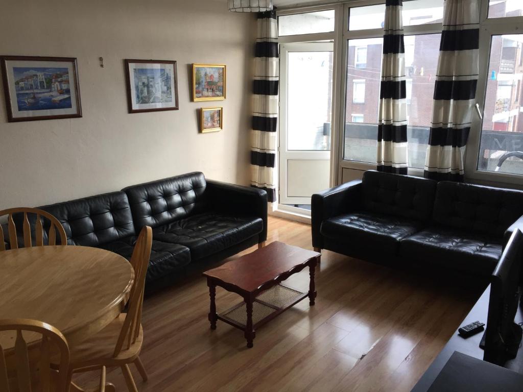a living room with a black couch and a table at Two bedroom apartment in Royal Greenwich in London