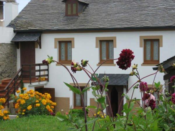 a white house with flowers in front of it at Apartamentos Rurales Romallande in Puerto de Vega