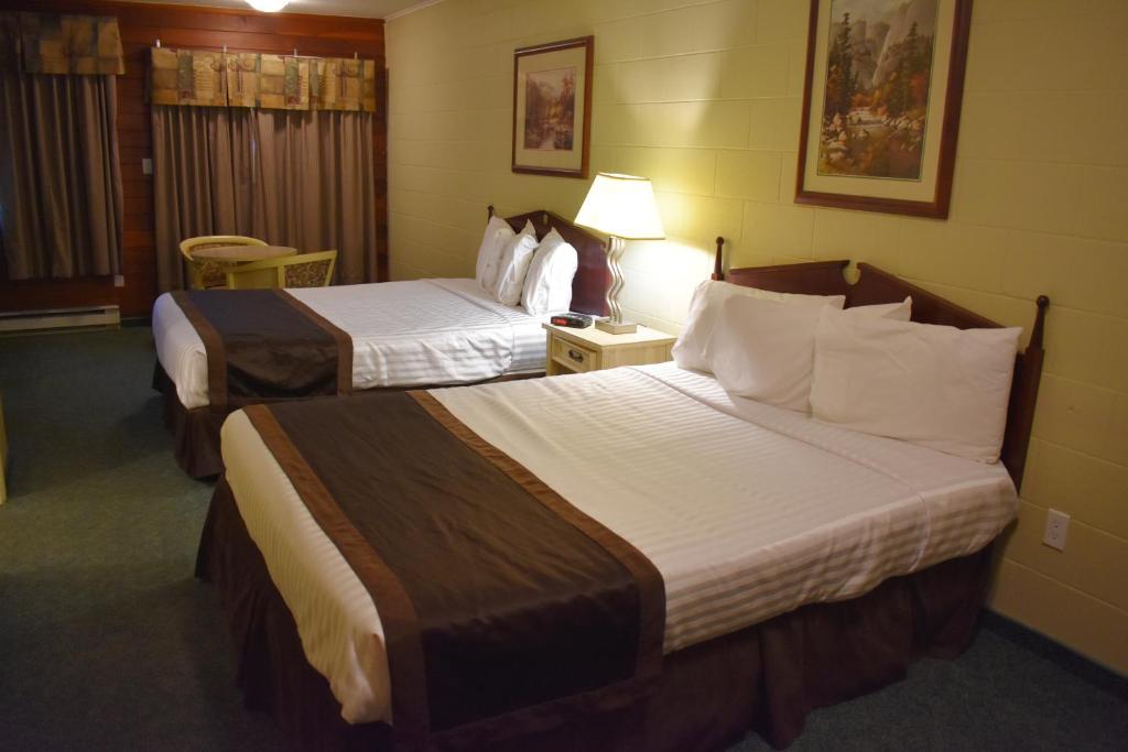 a hotel room with two beds and a lamp at Hope Inn and Suites in Hope