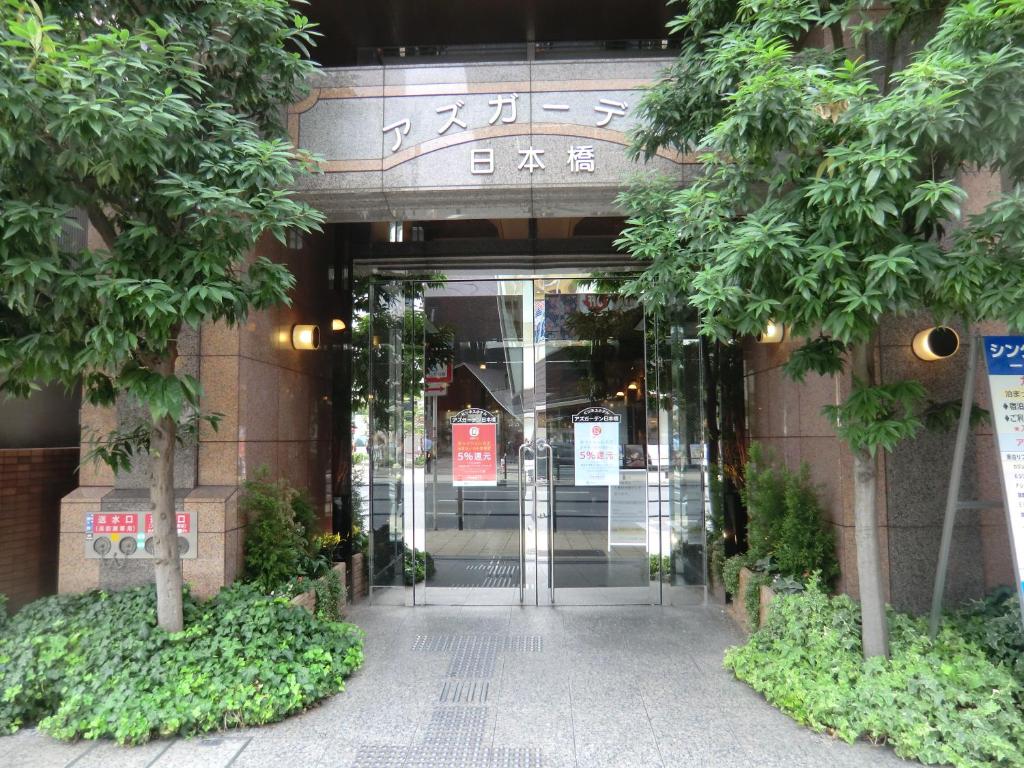 大阪市にあるアズガ－デン日本橋の木立の前の建物の入口