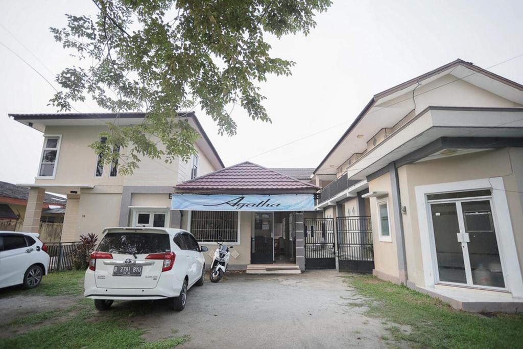 une voiture blanche garée devant une maison dans l'établissement RedDoorz near Bundaran Kecil Palangkaraya, à Palangka Raya