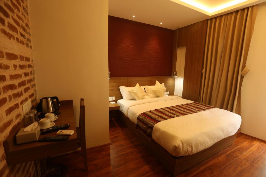 カトマンズにあるFlying Yak Kathmanduのベッド、デスク、コンピュータが備わるホテルルームです。